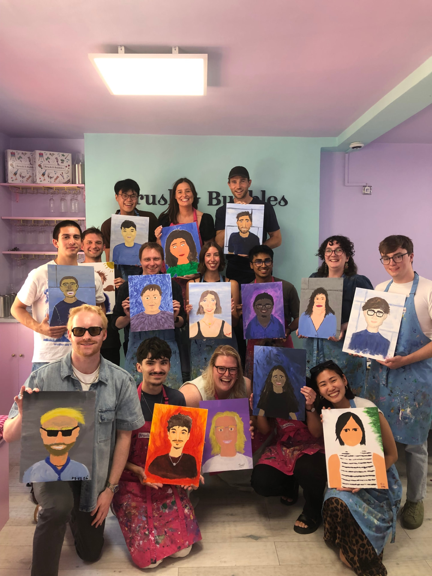 The Edify team together at a painting social, holding up portraits they painted of each other